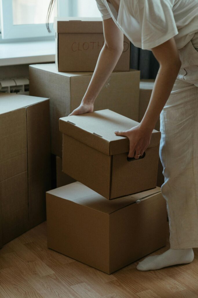 A woman packing cardboard boxes in her new apartment, symbolizing moving and relocation.